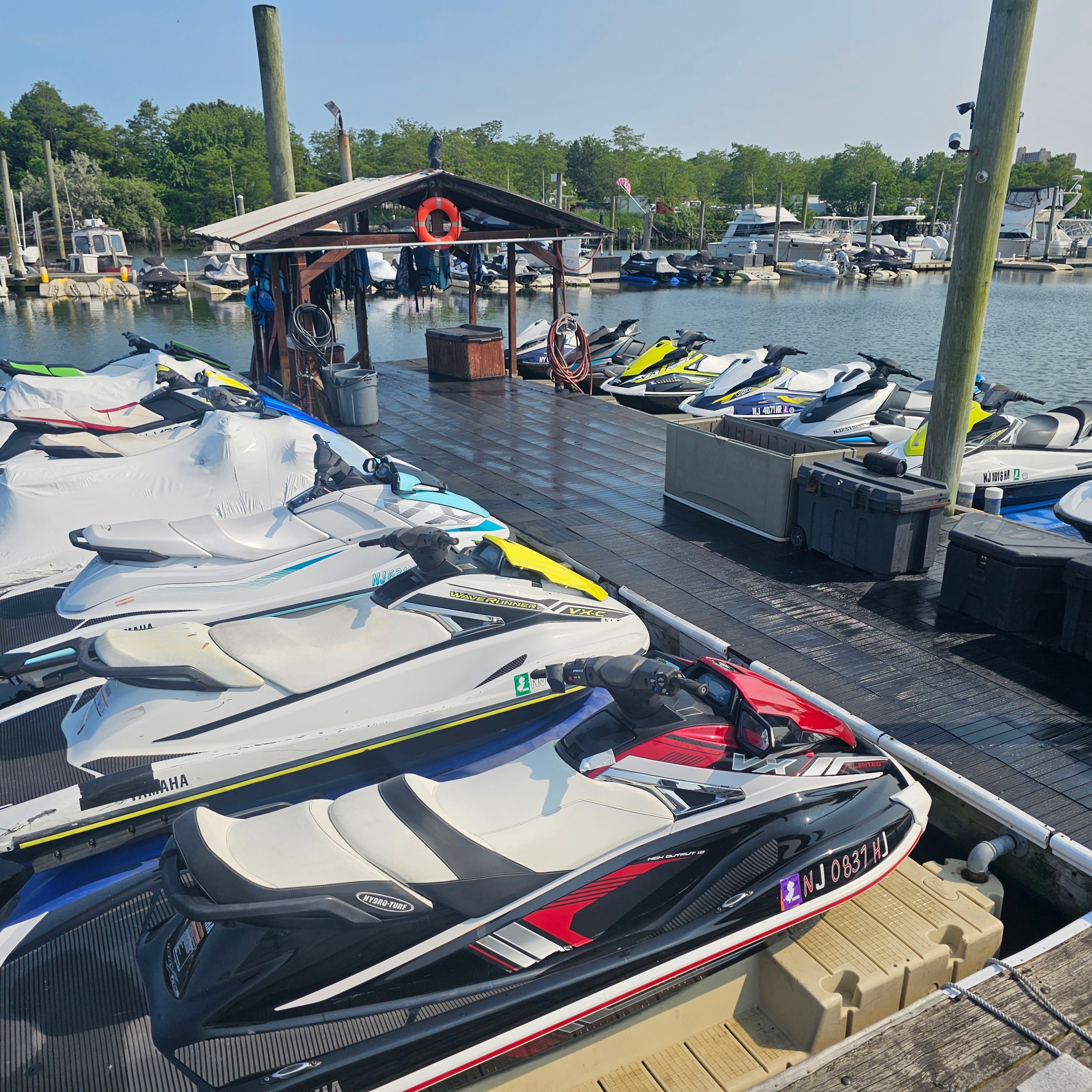 Multiple jet skis lined up on a wooden dock in a marina.