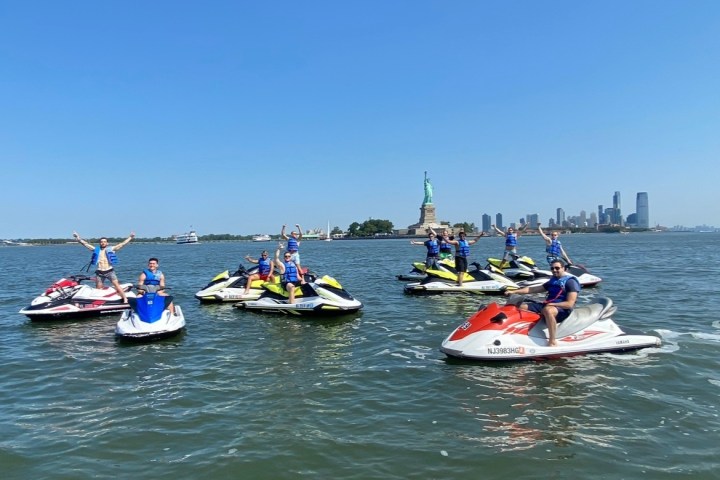 Group on jet skis near the Statue of Liberty on a sunny day.