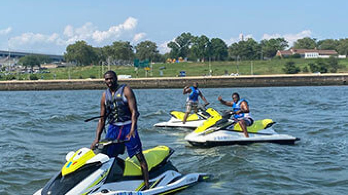 Three people on jet skis in a river on a sunny day.
