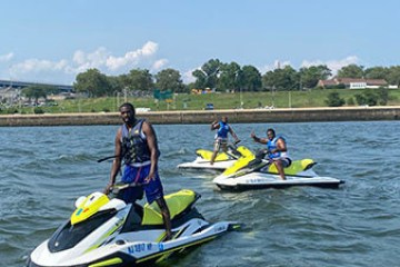 Three people on jet skis in a river on a sunny day.