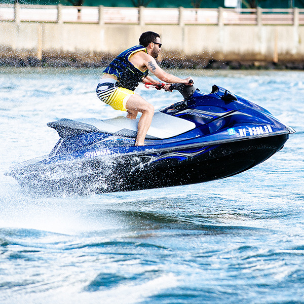 Man riding a jet ski on the water near a concrete wall.